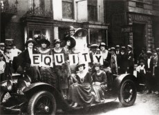 An old black and white photo displaying people riding a car in protest.