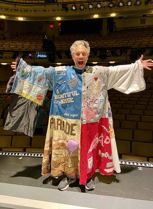 Jeffrey Schecter stands onstage, his back to the empty house, smiling in the Robe with his arms outstretched.
