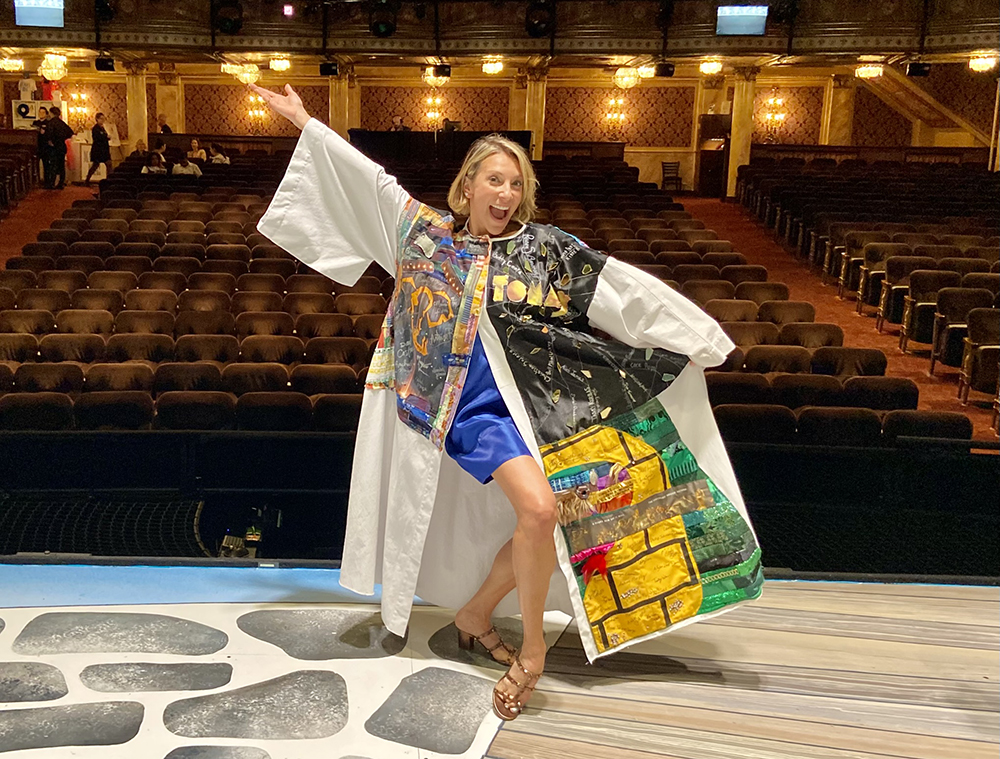 Erica Mansfield poses onstage in the Robe, one leg set forward and one arm up. The house seats are visible behind her.