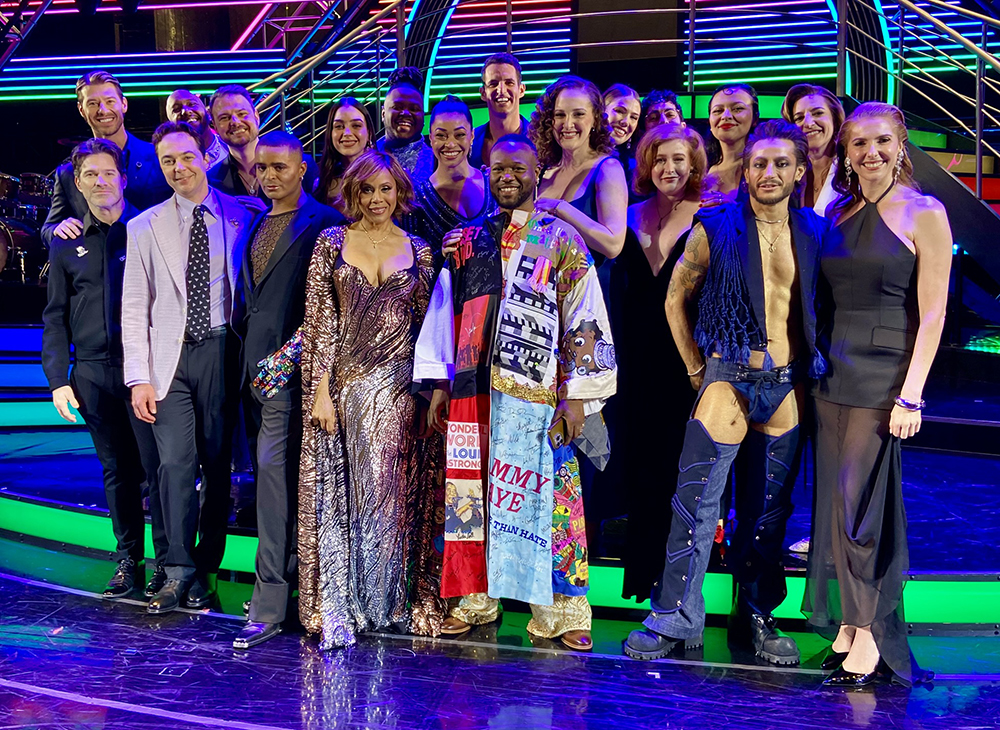 Polanco Jones, Jr. stands onstage in the Robe, surrounded by about 19 castmates.