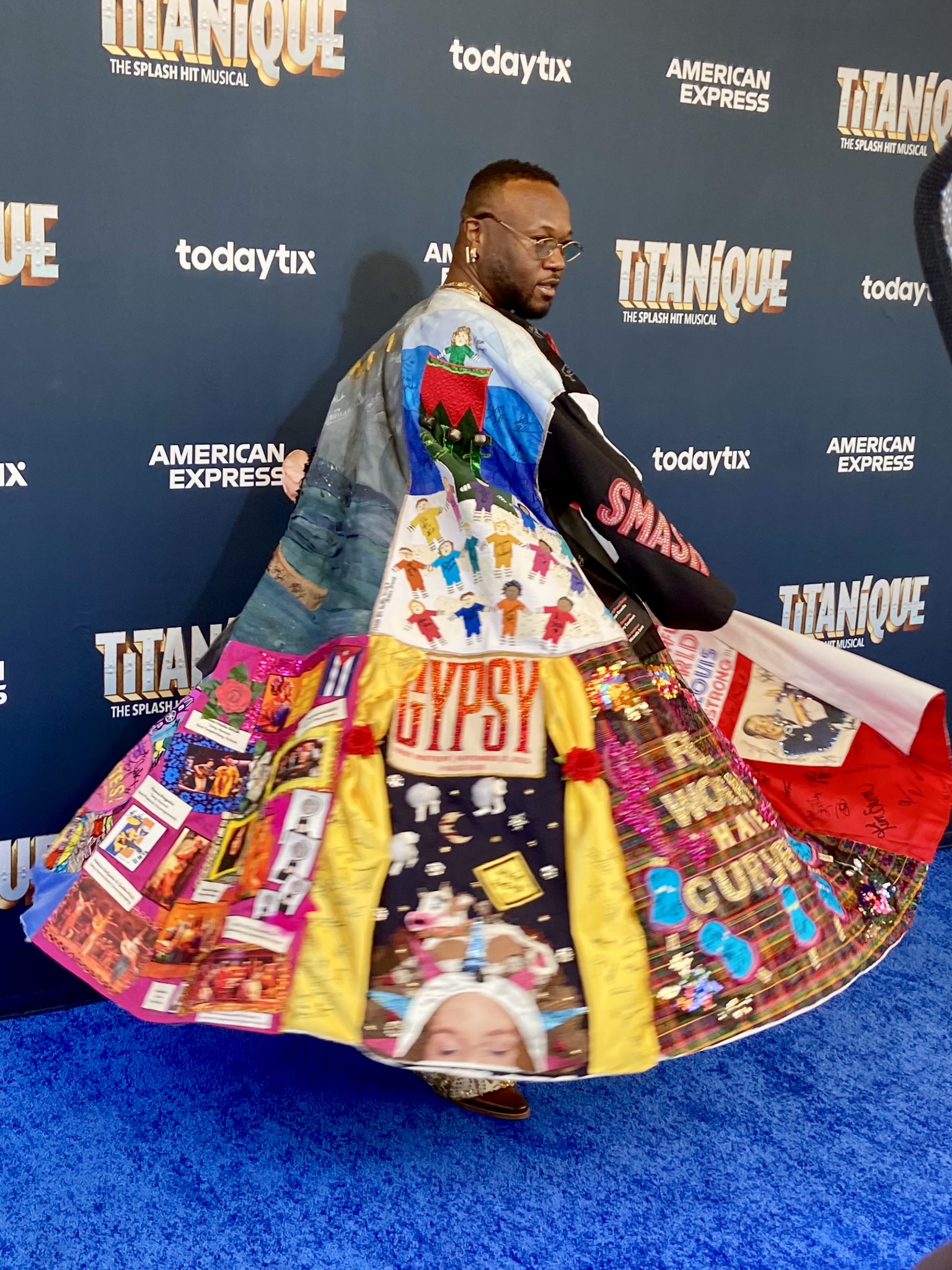 Polanco Jones., Jr. twirls in the Robe on a blue carpet in front of the step-and-repeat for 'Titanique.'